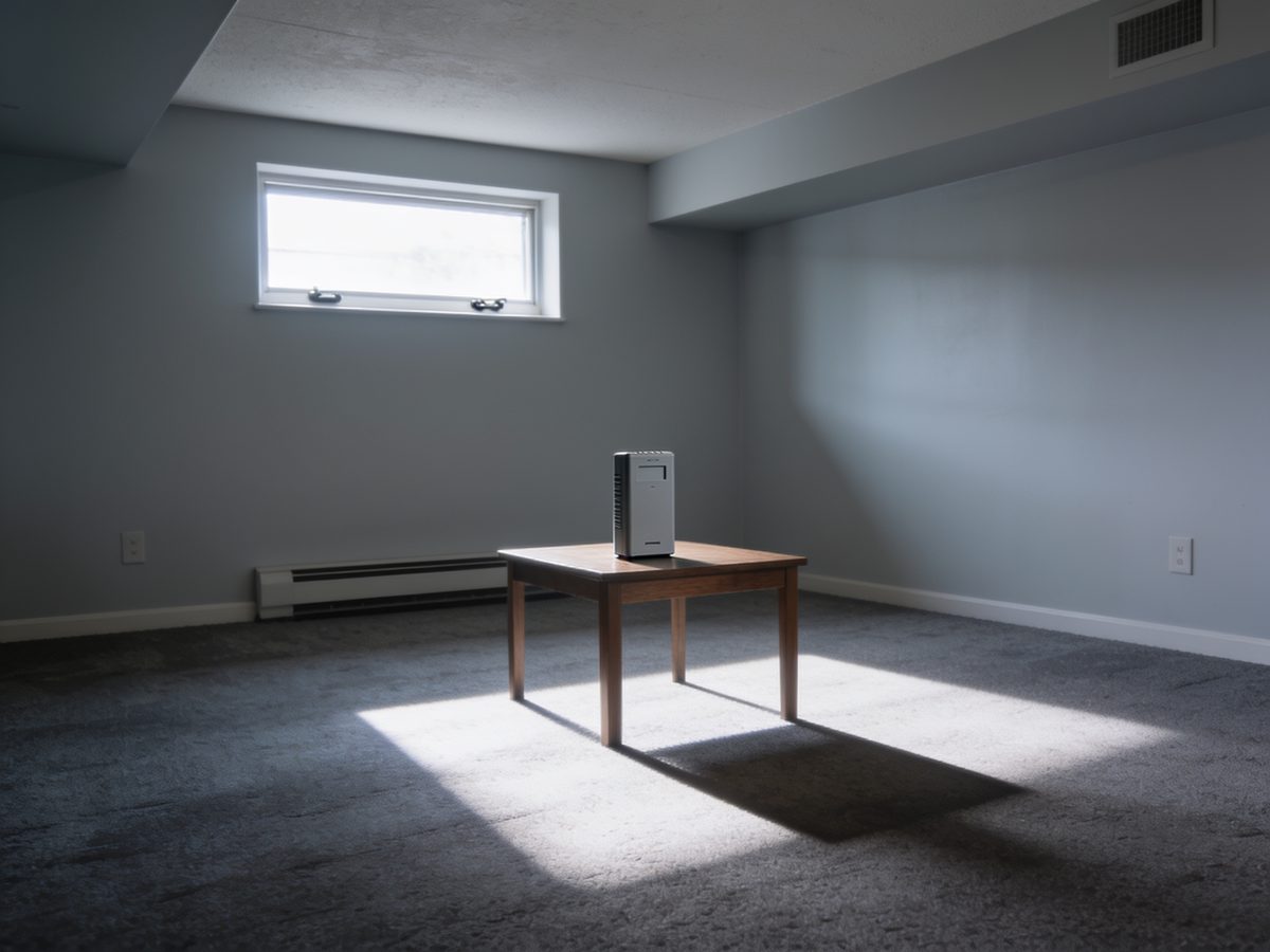 A radon monitor on a table in a finished basement below an egress window