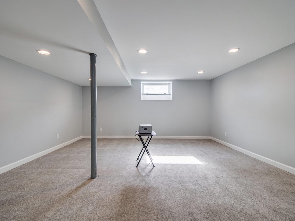 An empty finished basement with a radon monitor on a table in the middle of the room
